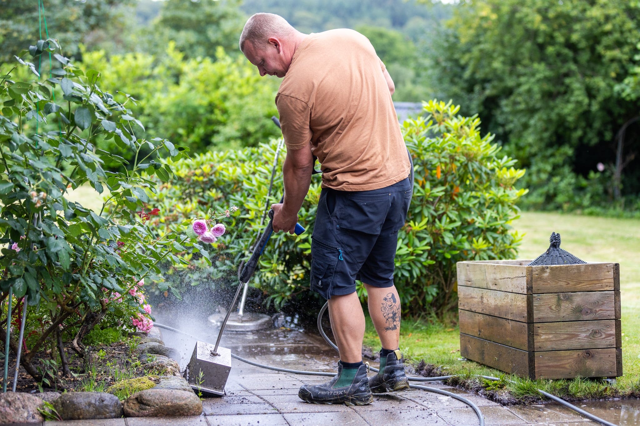 Mand renser fliser med højtryksrenser i haven