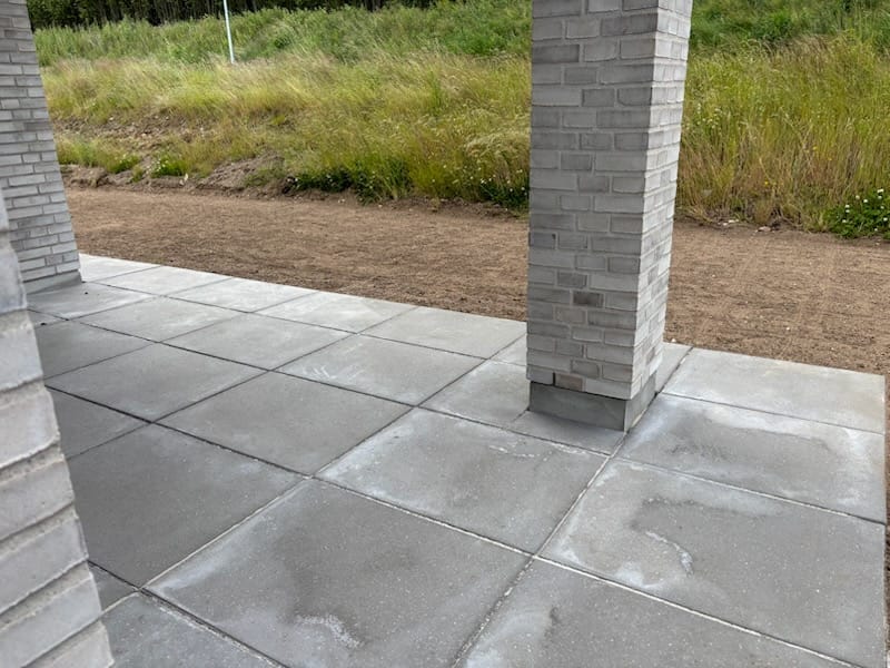 Ny flisebelagt terrasse med grå murstenssøjler